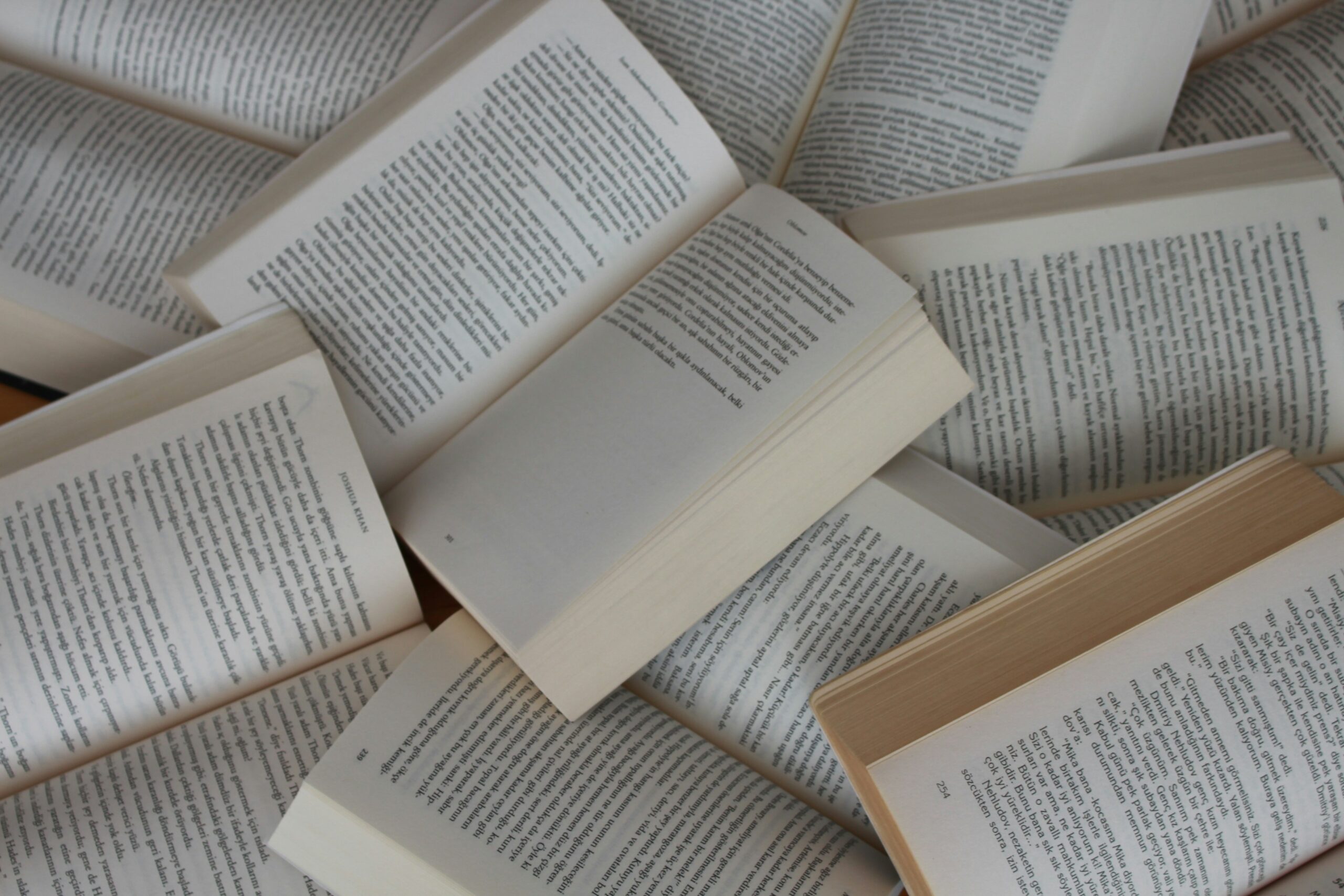 Diversos llibres oberts escampats, amb les pàgines de text a la vista.